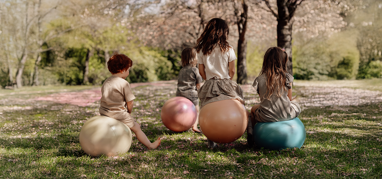 Group of children sitting on colorful bouncy balls from Find That Hippo in a spring park setting