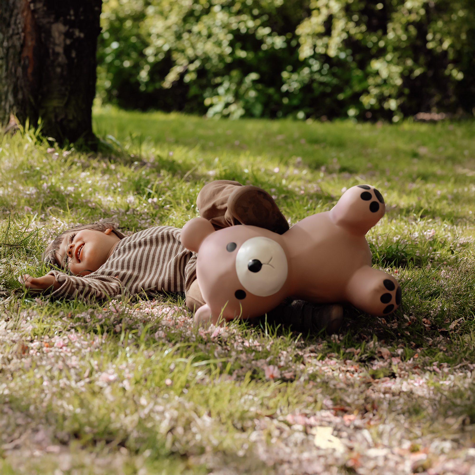 Child lying next to Maya the soft bouncing bear toy in the grass – Find That Hippo
