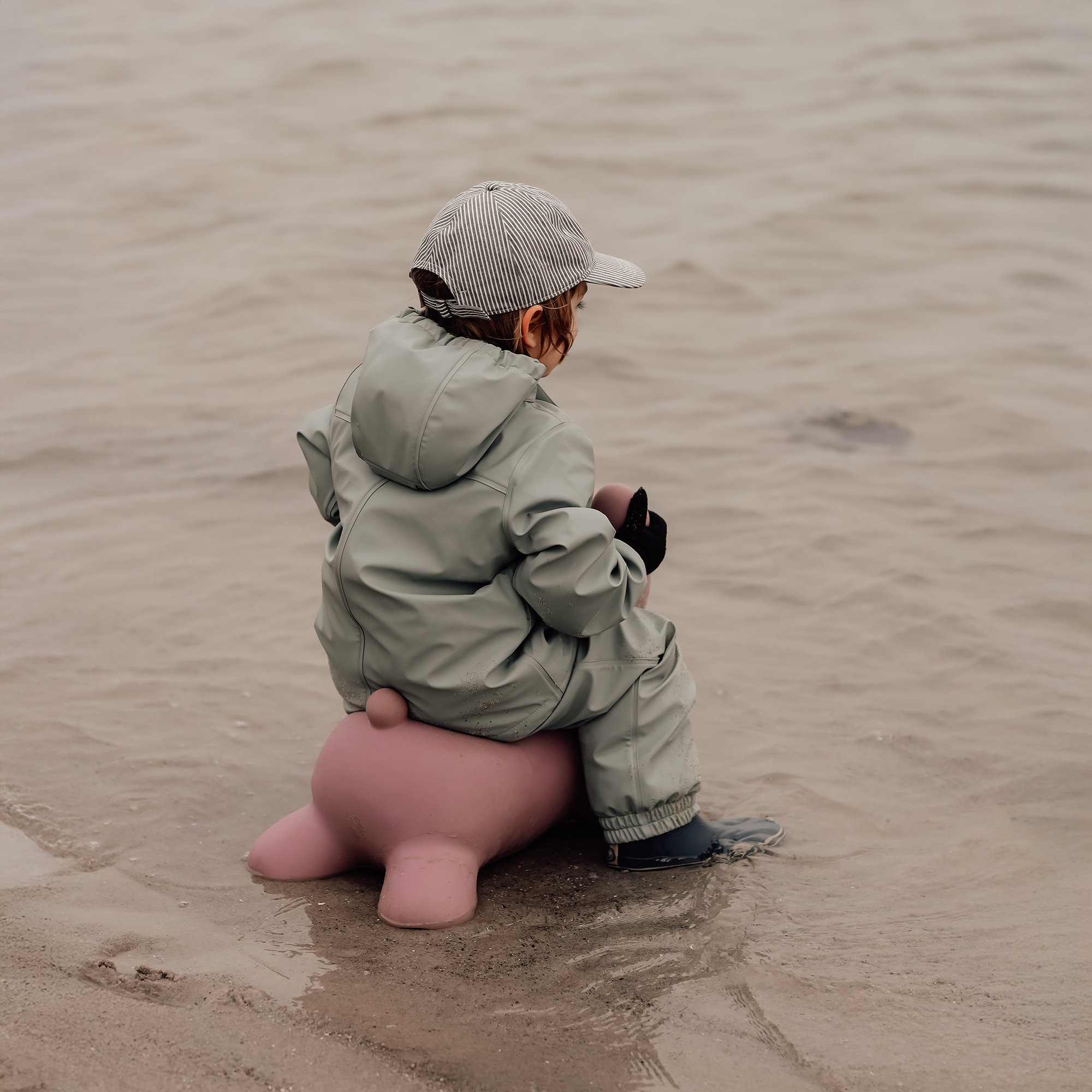Child riding Maya bouncing bear on the beach facing away – Find That Hippo