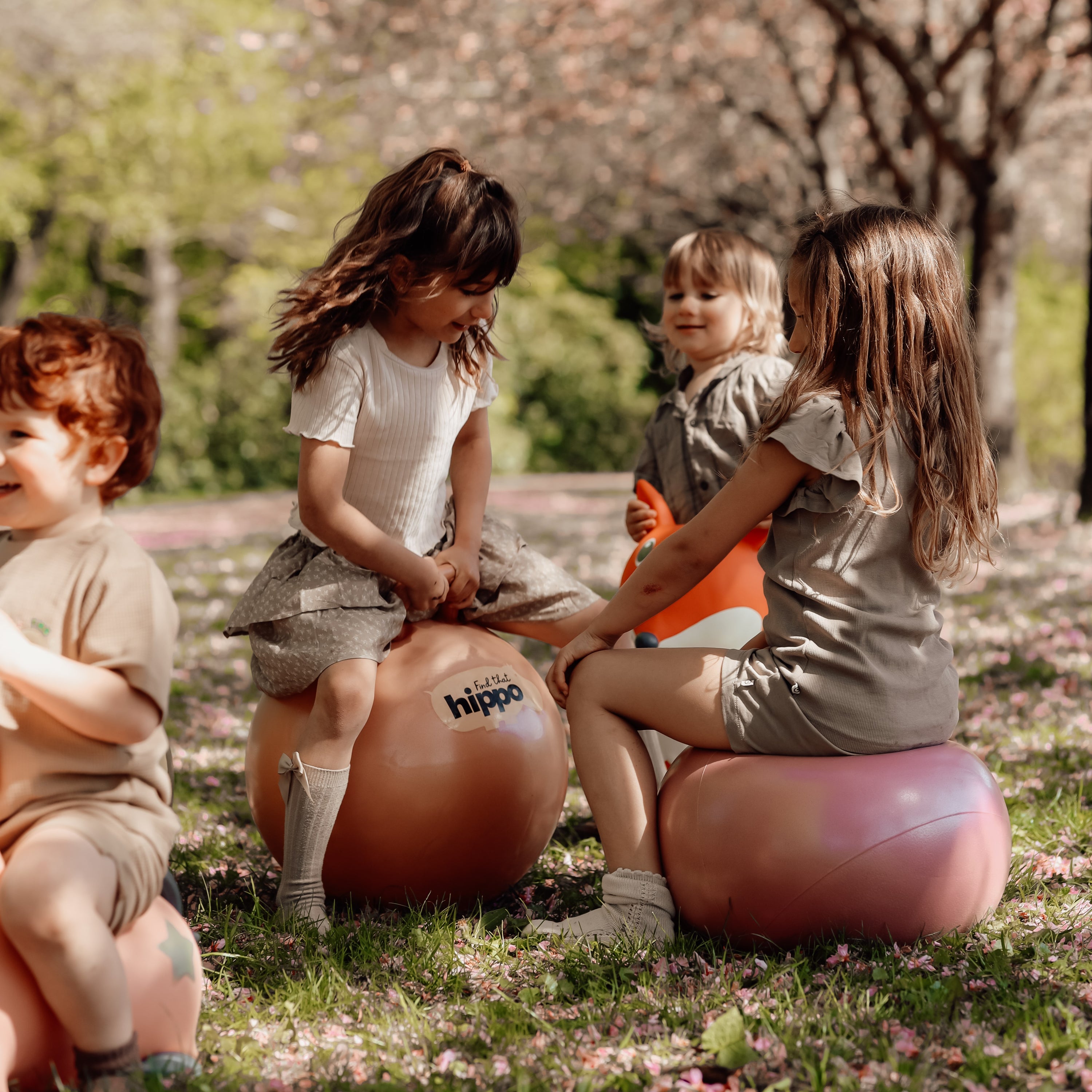 Four children sitting on bouncy balls outdoors – Find That Hippo