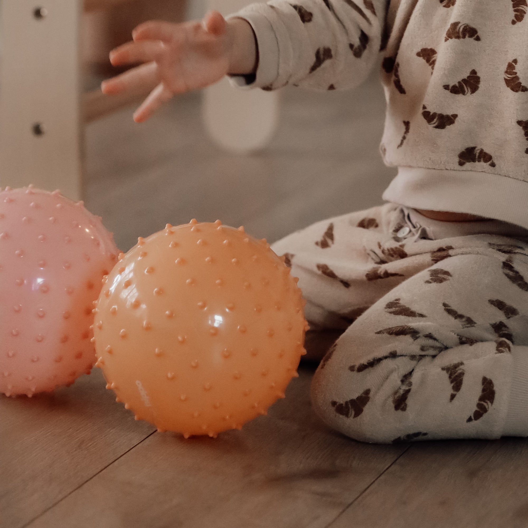 Small hands gripping an orange sensory ball in a cozy play area – Find That Hippo