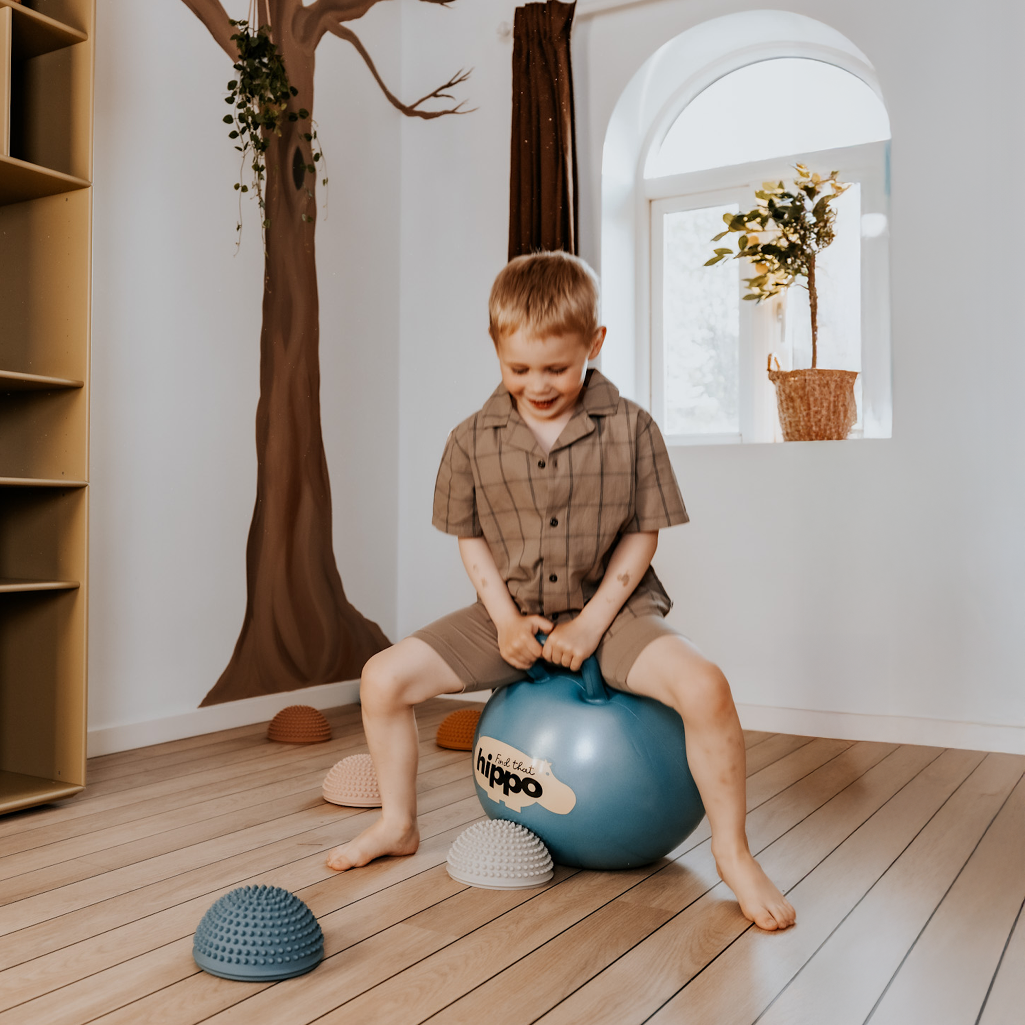 Child bouncing indoors on petrol blue Hippo hop ball – Find That Hippo