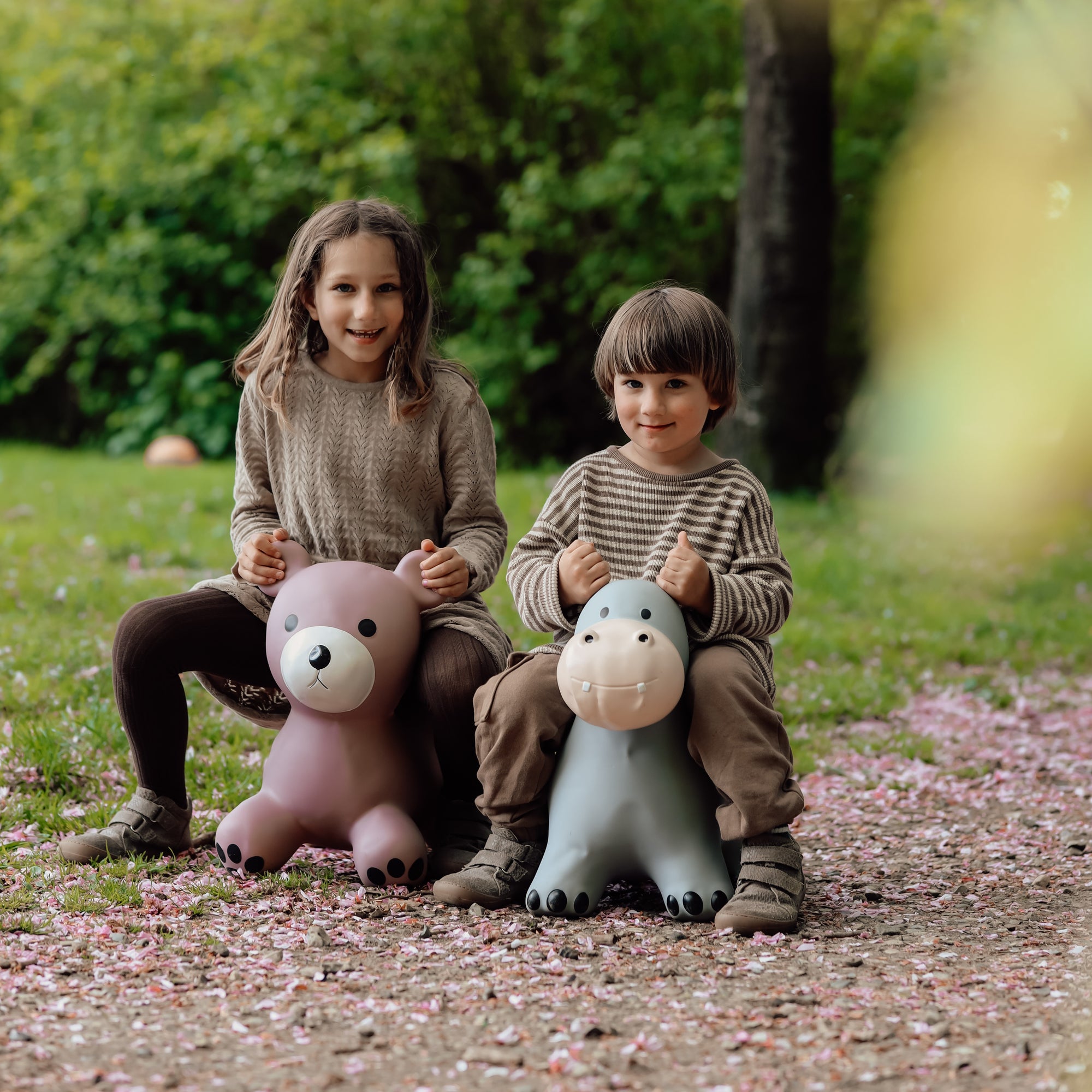 Two children sitting on bouncing toys including Holger the hippo in a forest setting – Find That Hippo