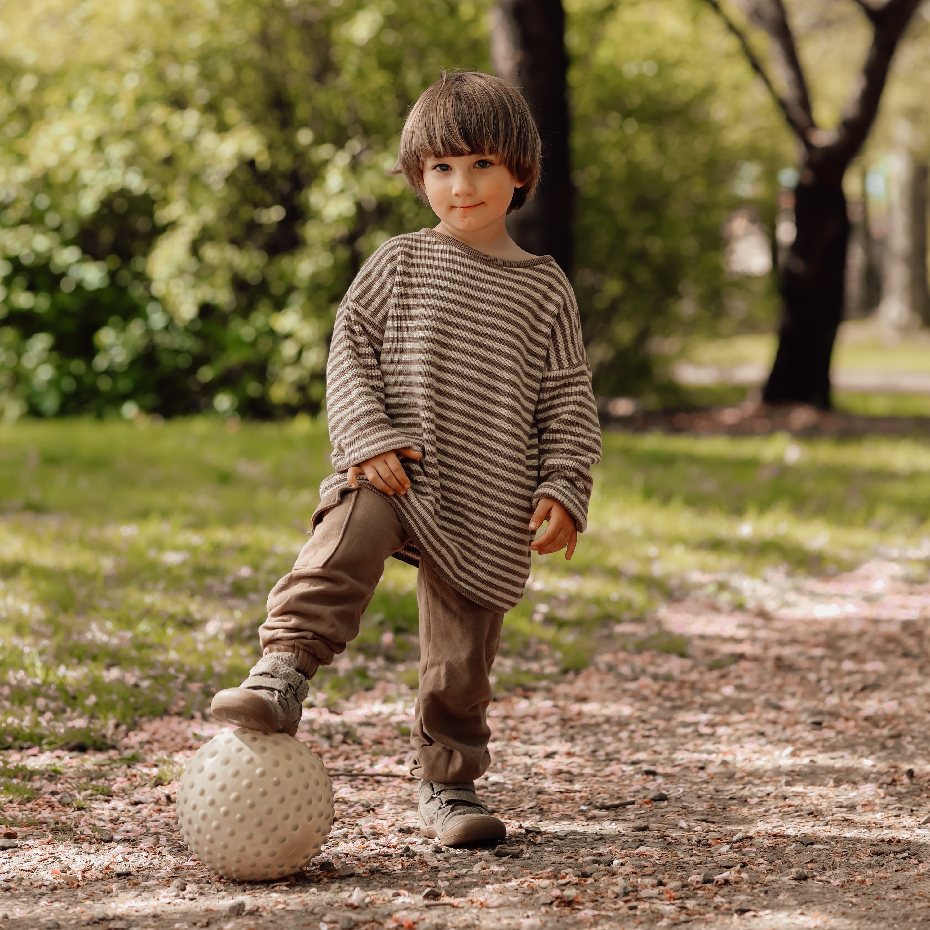 Child walking outdoors holding a dusty green sensory ball – Find That Hippo
