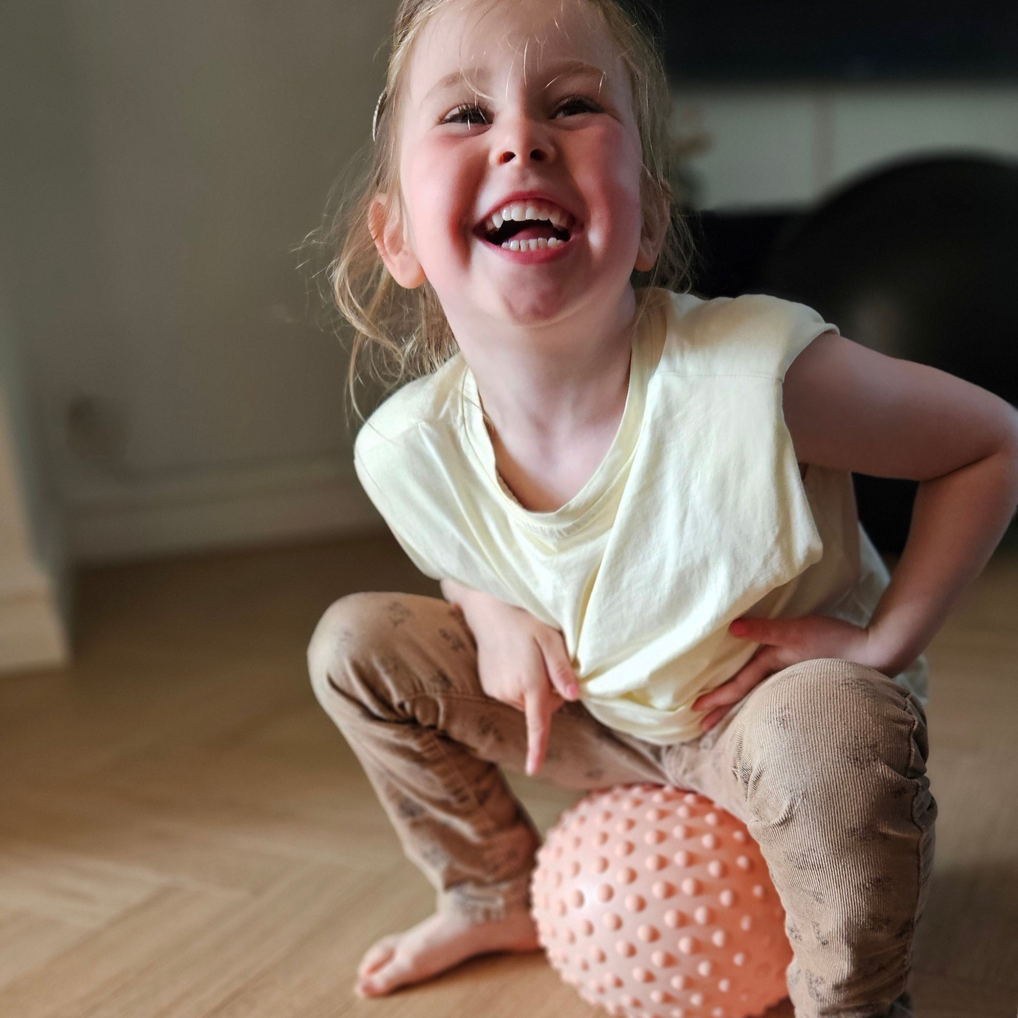 Laughing child sitting on a pink sensory ball – Find That Hippo