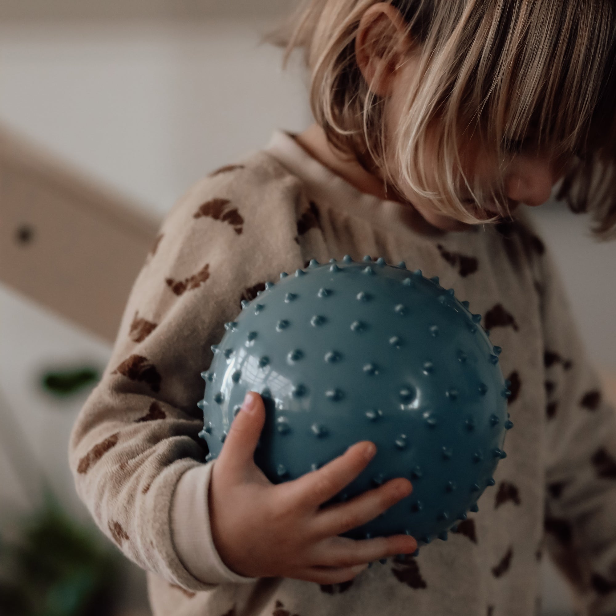 Baby holding a blue-colored sensory ball – Find That Hippo