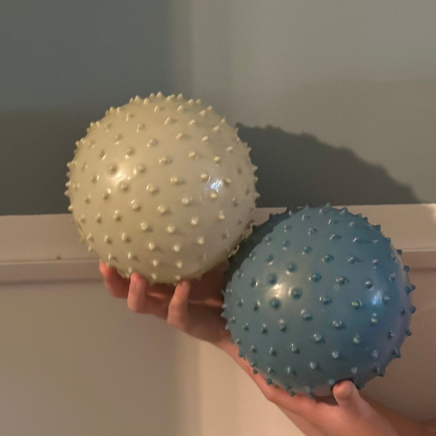 Close-up of child’s hands exploring khaki and blue sensory balls – Find That Hippo