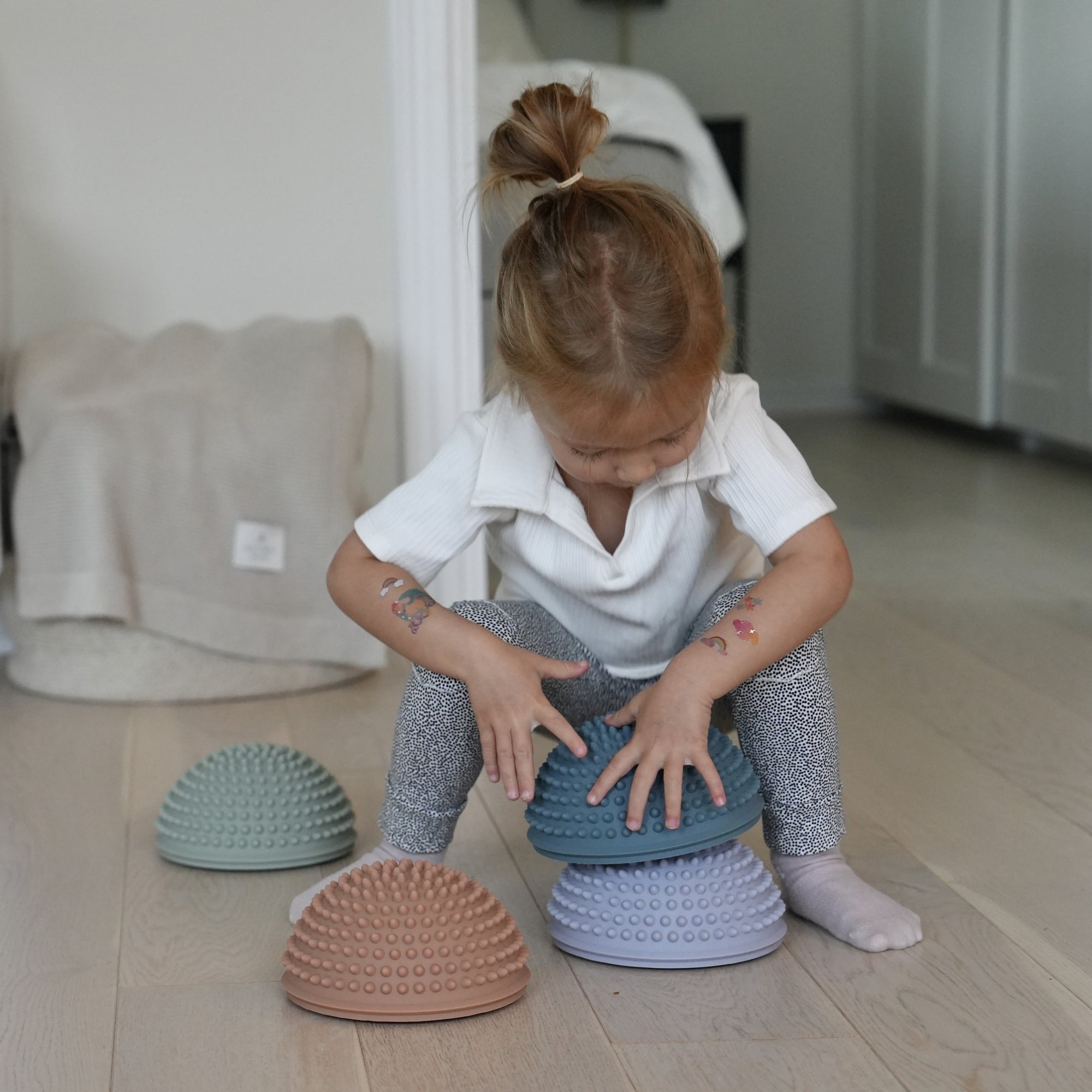 Young child carefully placing playing  with sensory stones in indoor setting – Find That Hippo