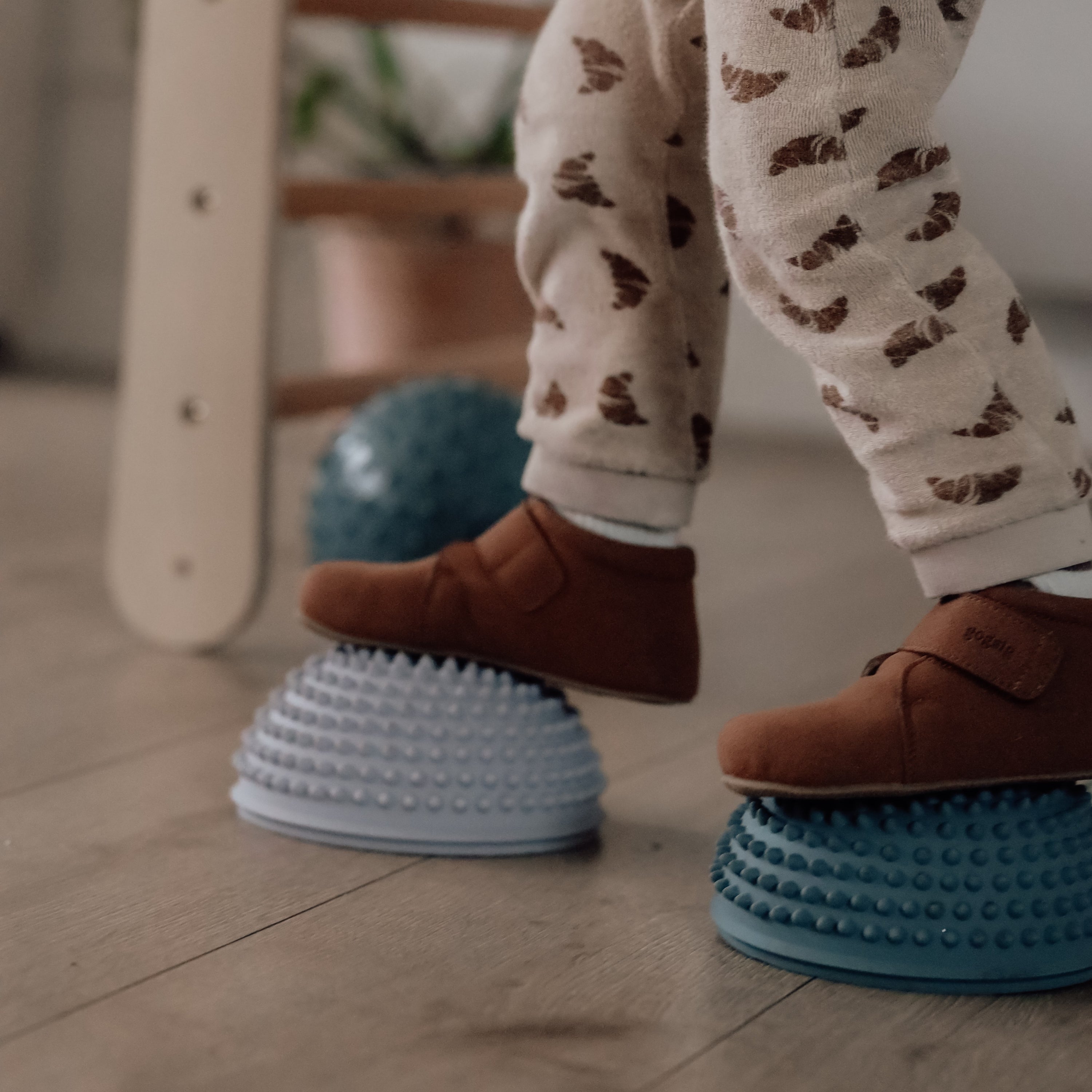 Close-up of child's feet standing on dusty green and orange sensory stones – Find That Hippo