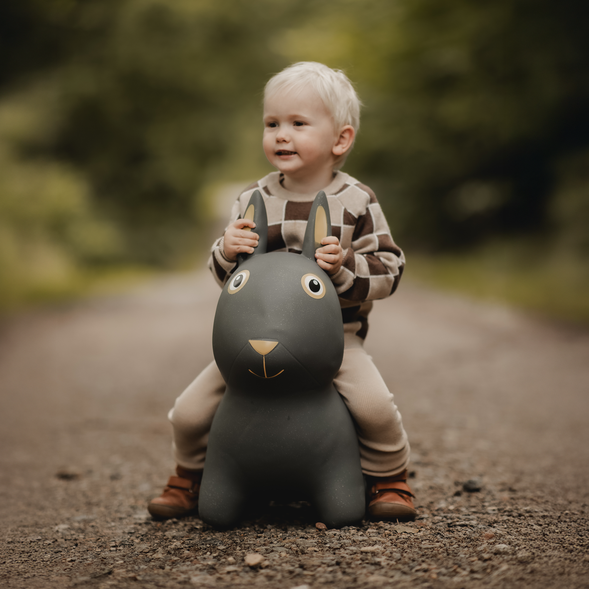 Child riding Thumper the dark grey bouncing bunny toy with white and beige details – Find That Hippo